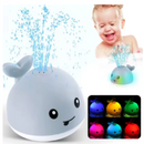 Bebê sorrindo enquanto brinca com o brinquedo baleia na banheira.