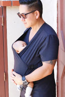 Homem com o Carregador Sling demonstrando ele instalado e com o bebê sentado adequadamente com as perninhas em y